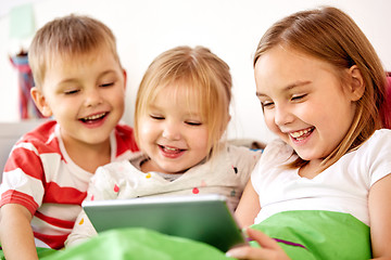 Image showing happy little kids with tablet pc in bed at home