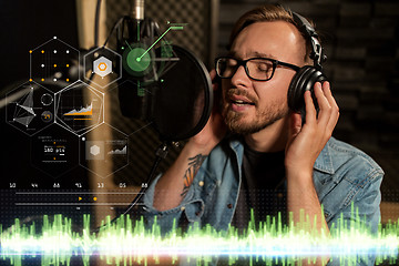 Image showing man with headphones singing at recording studio