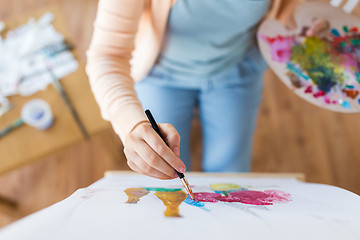 Image showing artist with palette and brush painting at studio