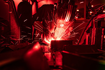 Image showing Welder in mask welding metal authentic shooting through red safe