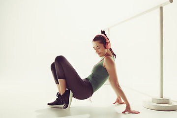 Image showing Front view of a young woman sitting with headphones