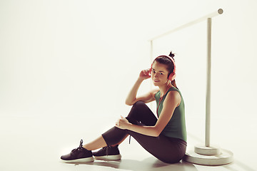 Image showing Front view of a young woman sitting with headphones