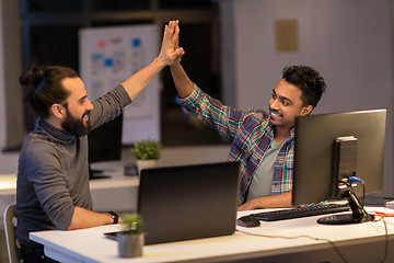 Image showing creative team making high five at night office