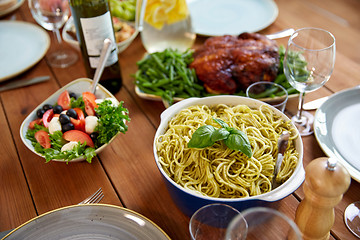 Image showing pasta with basil in bowl and other food on table