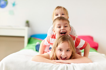 Image showing happy little kids having fun in bed at home