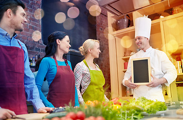 Image showing happy friends and chef cook with menu in kitchen