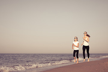 Image showing Mother and daughter running on the beach at the day time.