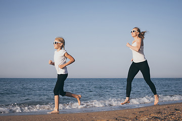 Image showing Mother and daughter running on the beach at the day time.