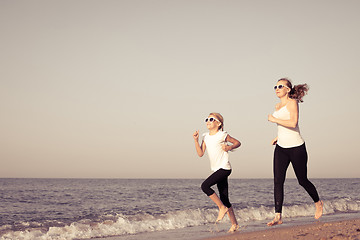 Image showing Mother and daughter running on the beach at the day time.