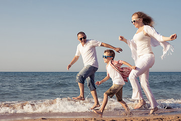 Image showing Happy family running on the beach at the day time.