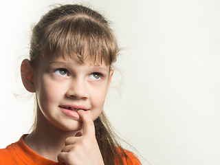 Image showing Portrait of a shy girl with a finger in her mouth, looking up thoughtfully
