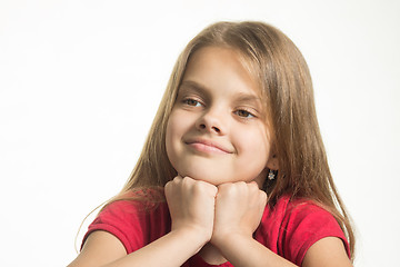 Image showing Portrait of a happy girl, she put her head on her fists and looks to the left