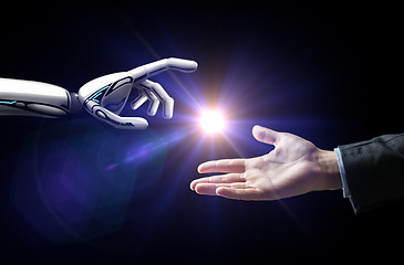 Image showing robot and human hand flash light over black