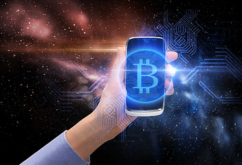 Image showing close up of hand with smartphone and bitcoin