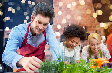 Image showing happy friends cooking and decorating dishes