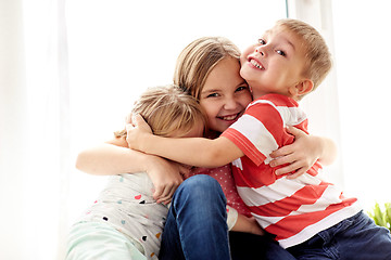 Image showing happy little kids hugging at window