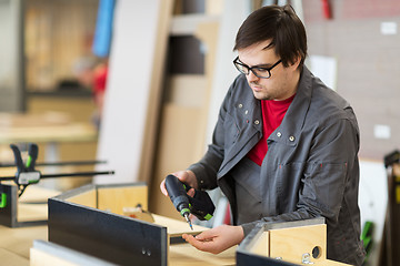 Image showing assembler with screwdriver making furniture