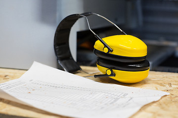 Image showing industrial earmuffs and bill on table at workshop