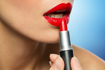 Image showing close up of woman applying red lipstick to lips
