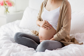 Image showing pregnant woman with bare belly sitting in bed