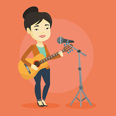 Image showing Woman singing in microphone and playing guitar.