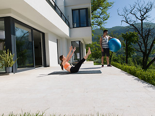 Image showing woman and personal trainer doing exercise with pilates ball