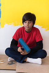 Image showing young boy painter resting after painting the wall