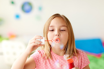 Image showing girl blowing soap bubbles indoors