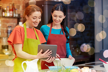 Image showing happy women with tablet pc cooking in kitchen