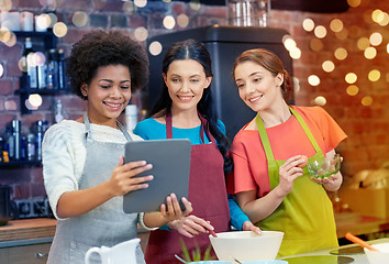 Image showing happy women with tablet pc cooking in kitchen