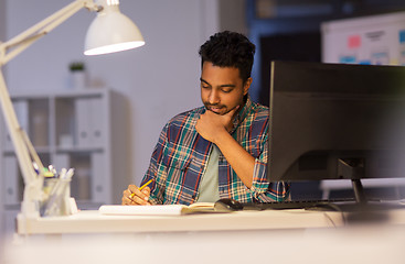 Image showing creative man with notebook working at night office