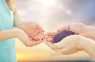 Image showing close up of father and daughter hands holding soil