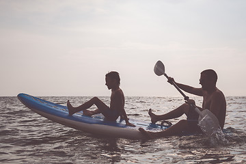 Image showing Father and son playing football on the beach at the day time.