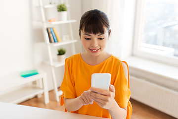 Image showing happy asian woman with smartphone at home