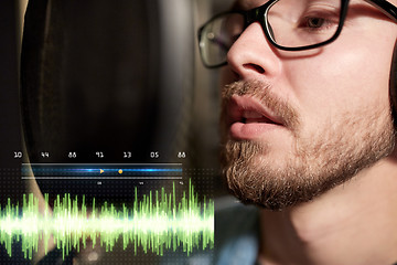 Image showing man with headphones singing at recording studio