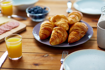 Image showing plate of croissants on wooden table at breakfast