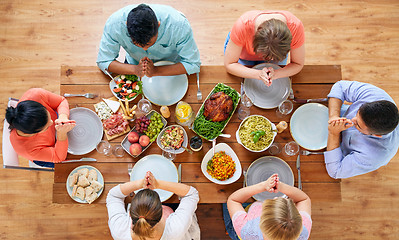 Image showing group of people at table praying before meal