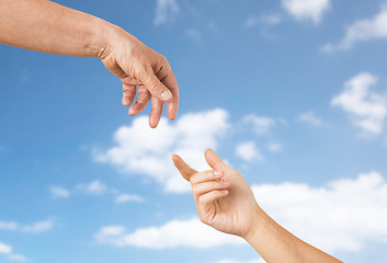 Image showing close up of senior and young woman hands over sky