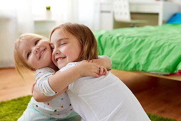 Image showing happy little girls or sisters hugging at home