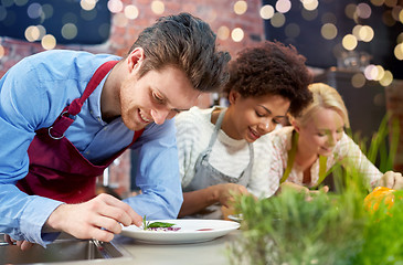 Image showing happy friends cooking and decorating dishes