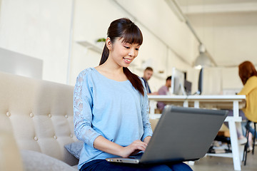 Image showing happy asian woman with laptop working at office