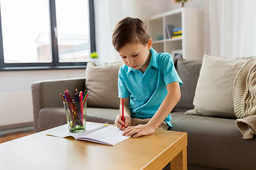 Image showing boy with notebook and pencils drawing at home