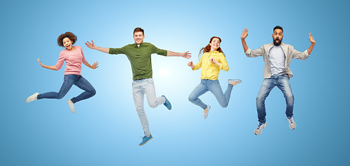 Image showing happy people or friends jumping in air over blue