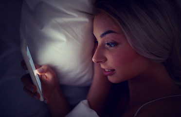 Image showing young woman with smartphone in bed at home bedroom