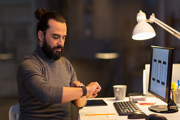 Image showing man with smartwatch and computer at night office