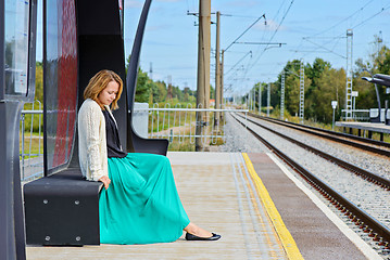 Image showing Young girl sitting on the railway station