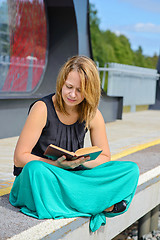 Image showing Woman sitting on the station and reading