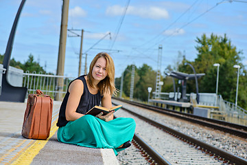 Image showing Woman sitting on the station and reading