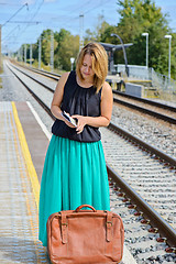 Image showing Woman standingon the station and reading