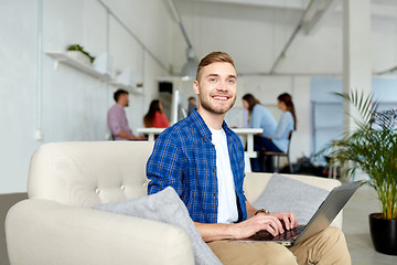 Image showing smiling man with laptop working at office